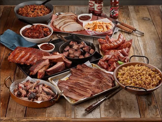A Joe's Bar-B-Que spread of smoked meats and sides laid out on a wooden table